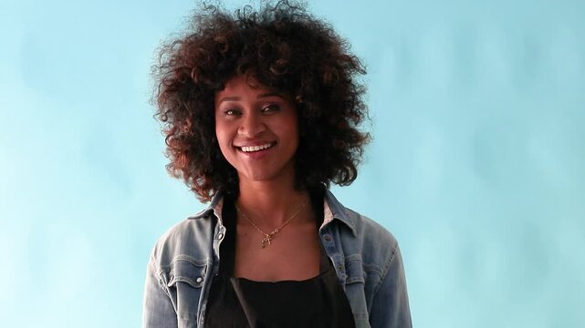 isolated portrait of a young latina woman with afro hair smiling