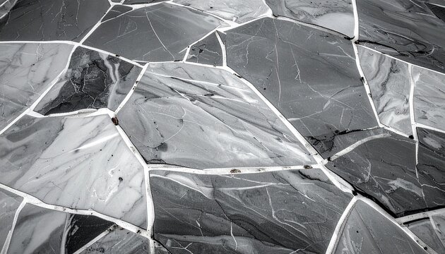 Abstract background of monochromatic stone floor with geometric cracked patterns and textured slate grey tiles for modern home design interiors.