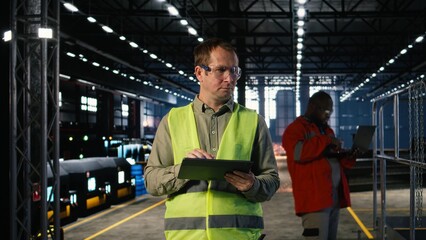 Fototapeta premium Technician in a warehouse inspects metal components with tablet, representing assembly tasks, professional engineering and the production workflow essential to industrial manufacturing.