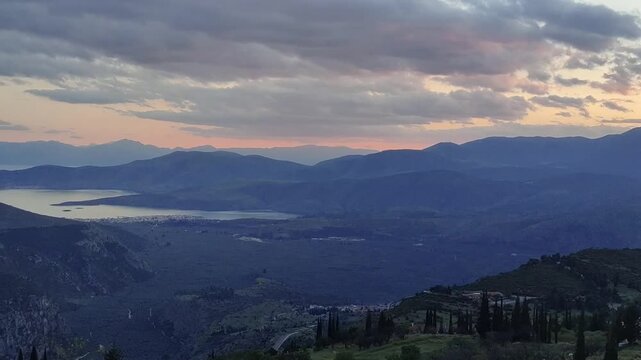 Serene blue hour landscape overlooking the Gulf of Itea from the heights of Delphi, Greece. Soft twilight sky over mountain silhouettes and the Mediterranean coast. Peaceful evening atmosphere