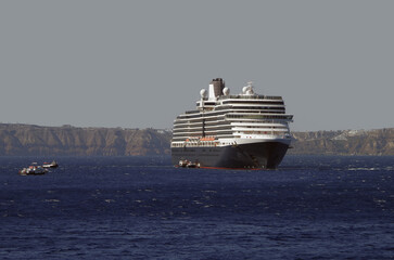 Luxury cruiseship cruise ship liner Eurodam anchoring at sea on sunny summer day during Mediterranean Greek Island Santorini caldera cruising with shore and rocky island in background © Tamme Wichmann