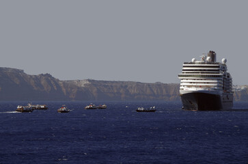 Luxury cruiseship cruise ship liner Eurodam anchoring at sea on sunny summer day during Mediterranean Greek Island Santorini caldera cruising with shore and rocky island in background © Tamme Wichmann