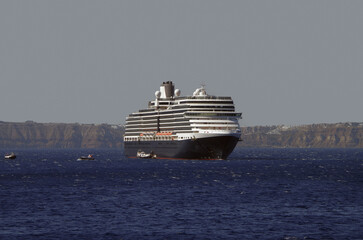 Luxury cruiseship cruise ship liner Eurodam anchoring at sea on sunny summer day during Mediterranean Greek Island Santorini caldera cruising with shore and rocky island in background © Tamme Wichmann