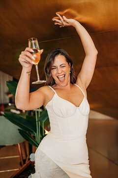 Joyful bride toasting champagne while dancing at reception