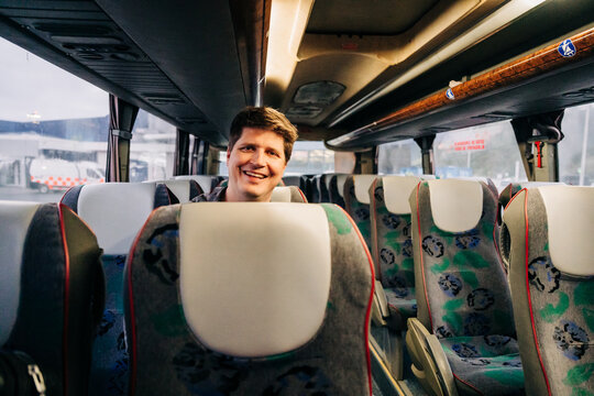 Smiling man sitting alone inside modern travel bus