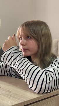Young blonde woman with bangs meticulously applying eyebrow gel with a spoolie brush, looking into a hand mirror to perfect her brow shape as part of her morning beauty regimen