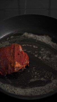 Placing marinated lamb topside roast on hot pan with oil