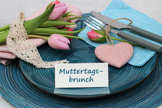 Muttertags-Brunch Gedeck mit rosa Tulpen und Herz auf blauem Teller