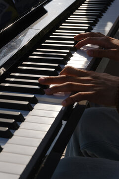 Hands Playing Piano Keys Close-up with Beaded Bracelets and Smartwatch