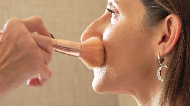 Woman, makeup, brush applying foundation to adult female face in close-up side profile for beauty routine.