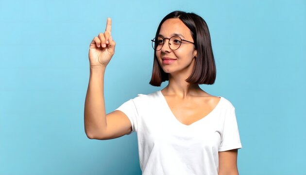 Mujer joven con gafas se&ntilde;alando hacia arriba sobre fondo azul en concepto de idea