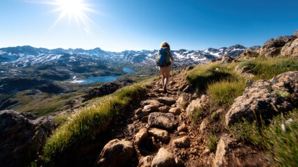 Fototapeta premium A lone hiker traverses a rocky path on a breathtaking mountain, highlighting the majestic landscape and the spirit of adventure in the great outdoors under a bright sky.