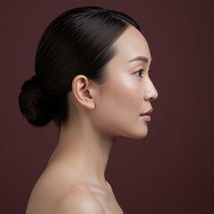 Side profile of a young East Asian woman with a serene expression for skincare advertising, beauty industry marketing and wellness salon branding on a dark background