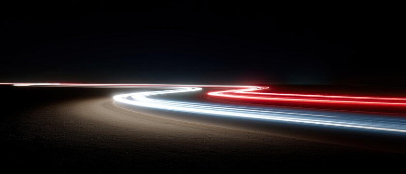Dramatic long-exposure photograph captures vibrant red white light trails sweeping along dark curving asphalt road.