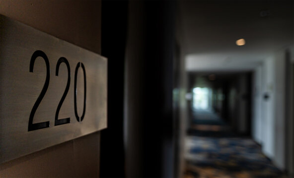 metal room number 220 plaque on a hotel wall with a blurred hallway background in a luxury apartment or hotel setting