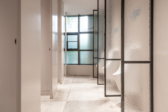Modern public restroom with glass partition doors and minimalist interior design