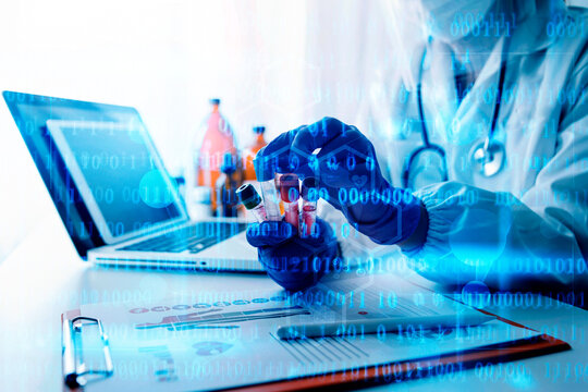 Doctor in lab coat and blue gloves holding a vial of medicine with a laptop and medical documents on a desk in a laboratory setting with blue digital overlay  medical technology concept