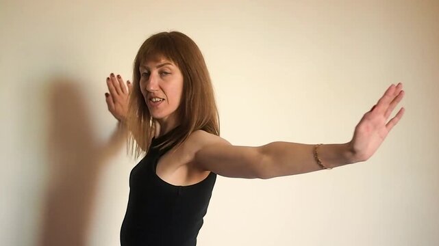 Horizontal video of athletic woman in black top doing wall pectoral stretch and shoulder mobility exercises,  fit girl practicing chest opening and flexibility for healthy posture and wellness