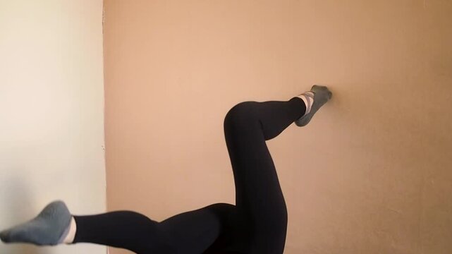 Horizontal video of fit female performing lower body stretching and back flexibility exercises on carpet at home or gym, trainer doing exercises for healthy posture and core stability in room
