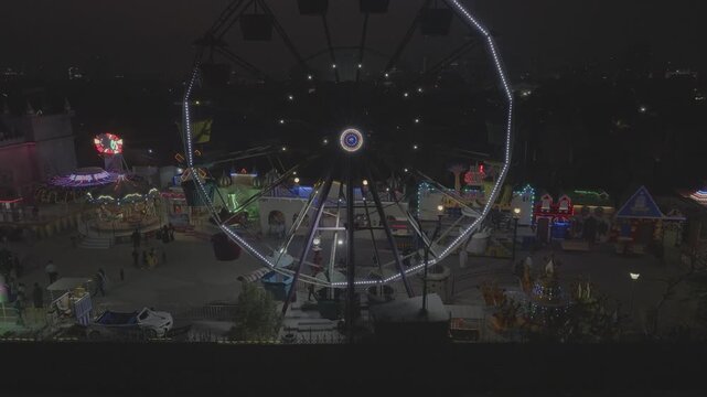 Lunapark in pakistan con giochi luminosi e uota panoramica di notte. Karachi. Ripresa con drone