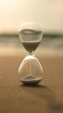 Glass hourglass on a sandy shore glowing in golden sunlight, representing time, waiting, deadlines, change, reflection, and the precious balance between past, present, and future.