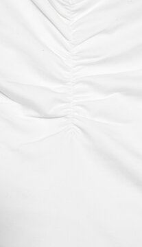 shot of white fabric featuring a central vertical seam with gathered, ruched detailing that creates soft, radiating pleats