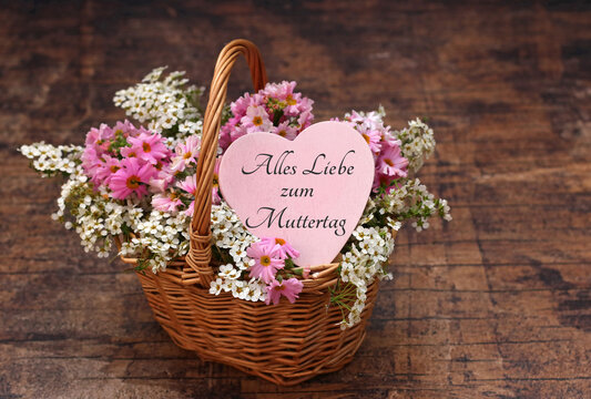 Alles Liebe zum Muttertag. Herzlicher Muttertagsgru&szlig; im Weidenk&ouml;rbchen mit Fr&uuml;hlingsblumen auf rustikalem Holz.