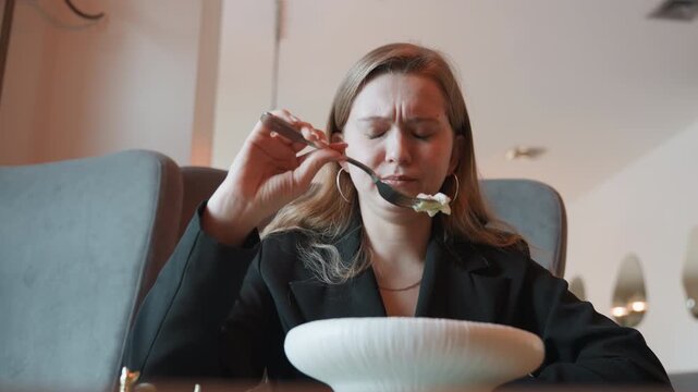 Diner examines her meal quietly. Woman observes her salad with doubt at fine dining establishment. Female guest evaluates her meal with suspicion and careful attention in upscale restaurant