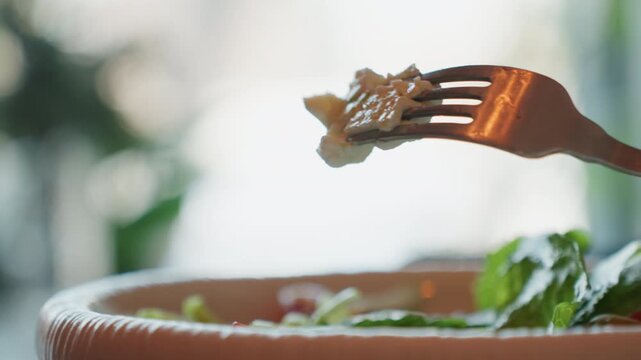 Fork lifting creamy bite over salad in soft natural backlight, shallow depth of field shows fresh lettuce and mint, homemade dressing glistening on bowl rim, slow cinematic motion captures calm home