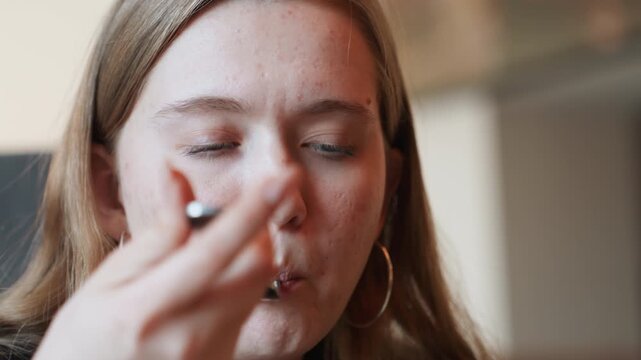 Young woman savoring bite with smile, satisfied wellness enthusiast reacts to fresh leafy salad, subtle head tilt and closed eyes moment, hoop earring detail, soft cafe interior lighting, emotive