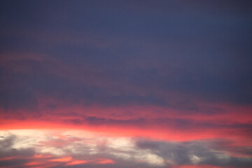 Fototapeta premium Beautiful sunset sky blending orange, yellow, and gray hues, creating a calm, dramatic atmosphere with soft glowing clouds.