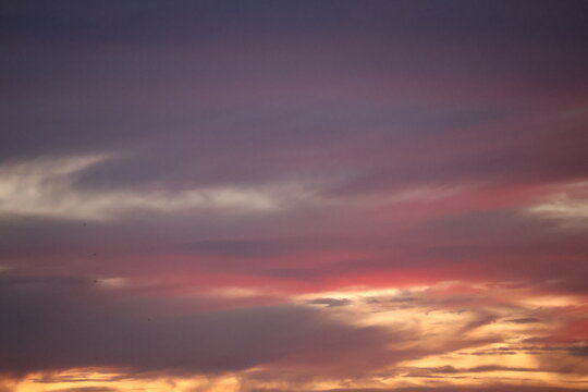 Beautiful sunset sky blending orange, yellow, and gray hues, creating a calm, dramatic atmosphere with soft glowing clouds.