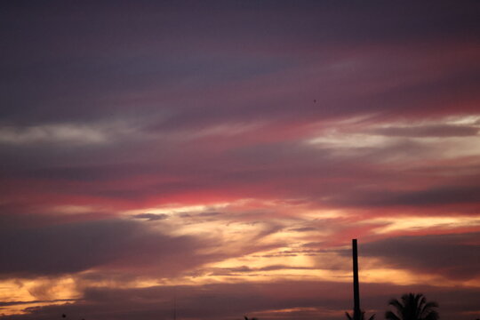 Beautiful sunset sky blending orange, yellow, and gray hues, creating a calm, dramatic atmosphere with soft glowing clouds.