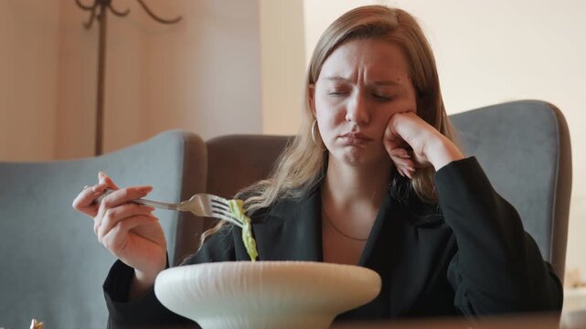 Caucasian woman frustrated with salad refusal in dim cafe, blazerclad office manager pushes fork from bowl, slumped posture, frown, natural window light, closeup on expression, moody palette,