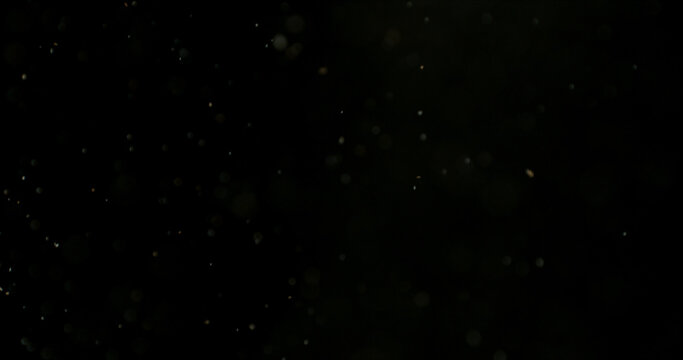 Close-up of floating dust particles in air, isolated on black background. Minimalist abstract texture with soft light, designed as VFX overlay for compositing.