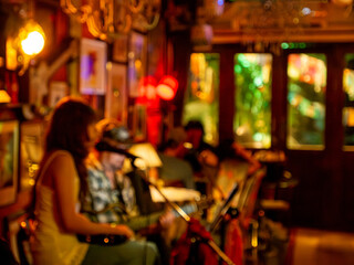Blurred defocused live music jazz band performance inside cozy vintage bar with warm golden red bokeh ambiance nightlife © Tavan