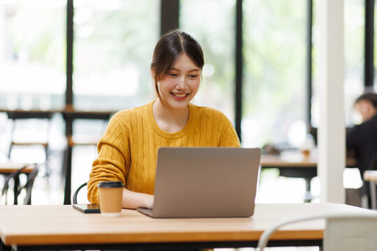 Smiling asian woman using laptop for remote work