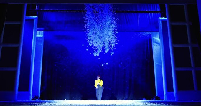 The clown actor and the falling confetti snowflakes create a stage performance effect.