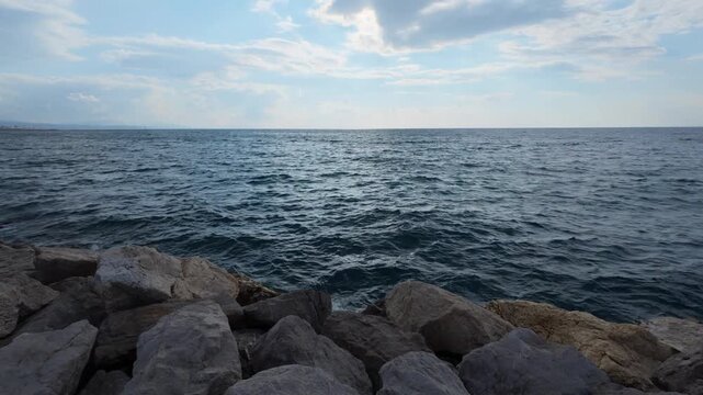 Dark wavy sea under heavy sky with stone breakwater and wide horizon