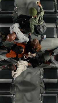 Vertical video Passengers in busy airport bumping into each other while hurrying to catch plane, top down view. Stressed people rushing in busy departure terminal bashing their trolleys, high angle