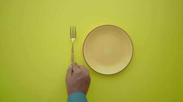 Hand placing yellow plate on yellow background