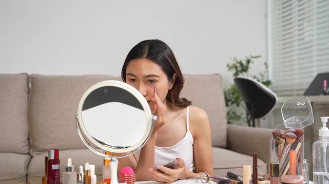 Asian beauty influencer recording makeup tutorial at home with smartphone, skincare and cosmetics content creator livestream.