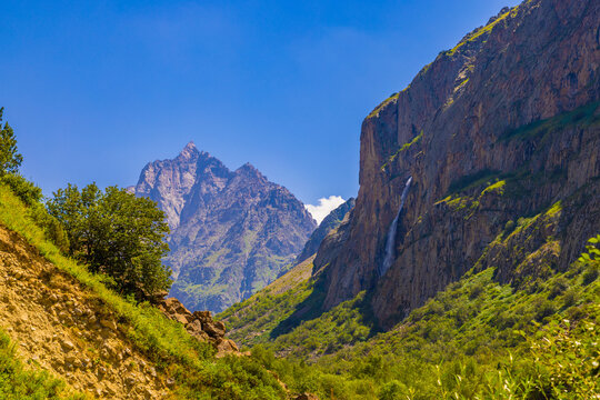 Majestic mountain peaks and waterfall in lush valley