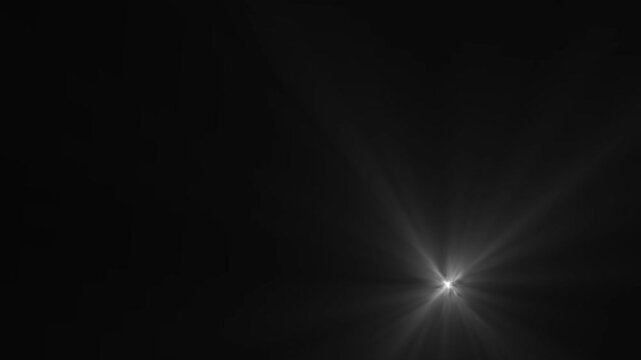 Bright white optical flare light beam shining from lower right corner of black background creating rays.
