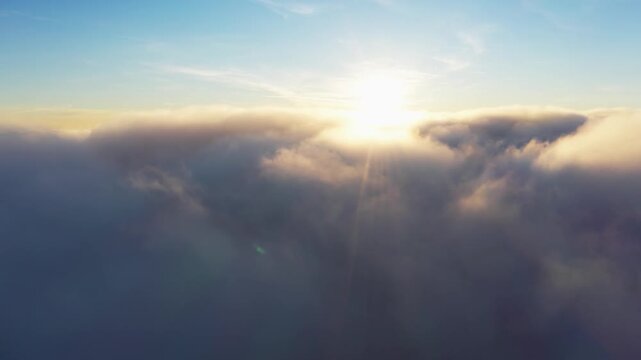 Sun shining brightly above white fluffy clouds at sunrise