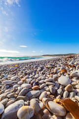 Obraz premium Tranquil coastline landscape with azure sky, sand, rocks, and gentle waves
