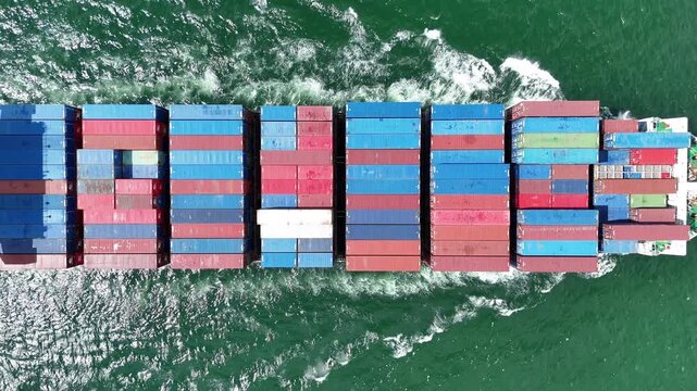 container ship fully loaded with colorful cargo containers being assisted by tugboats in the open sea. Concept of global maritime logistics, international trade, and heavy shipping operations.	