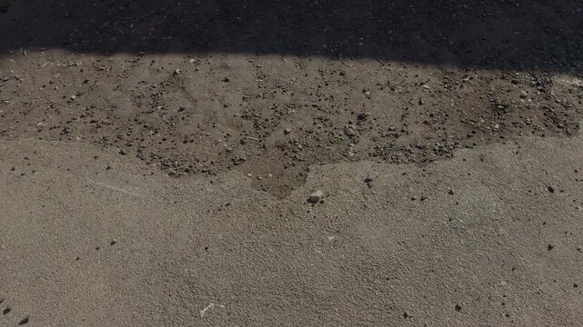 Damaged paving indicating repairs needed. Surface wear reveals structural aging and fragility. Worn out asphalt with debris and potholes shows significant infrastructure degradation