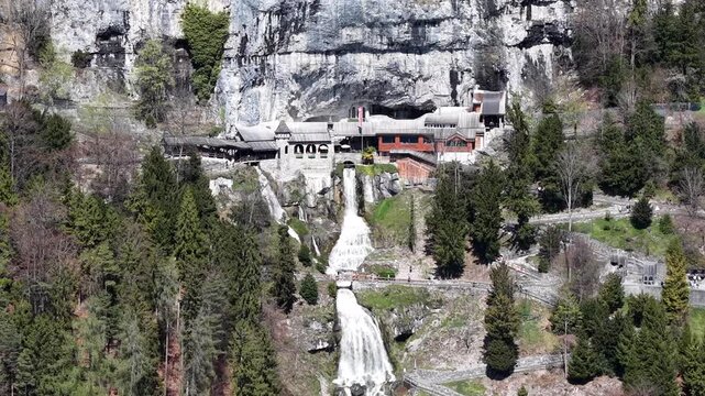 Aerial View of Saint Beatus Caves Entrance with Waterfall and Historic Buildings, Lake Thun, Switzerland