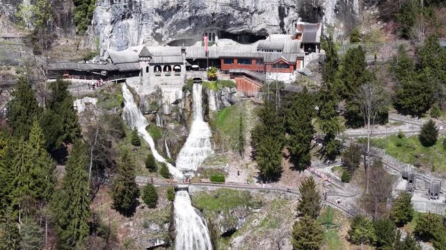 Aerial View of Saint Beatus Caves Entrance with Waterfall and Historic Buildings, Lake Thun, Switzerland